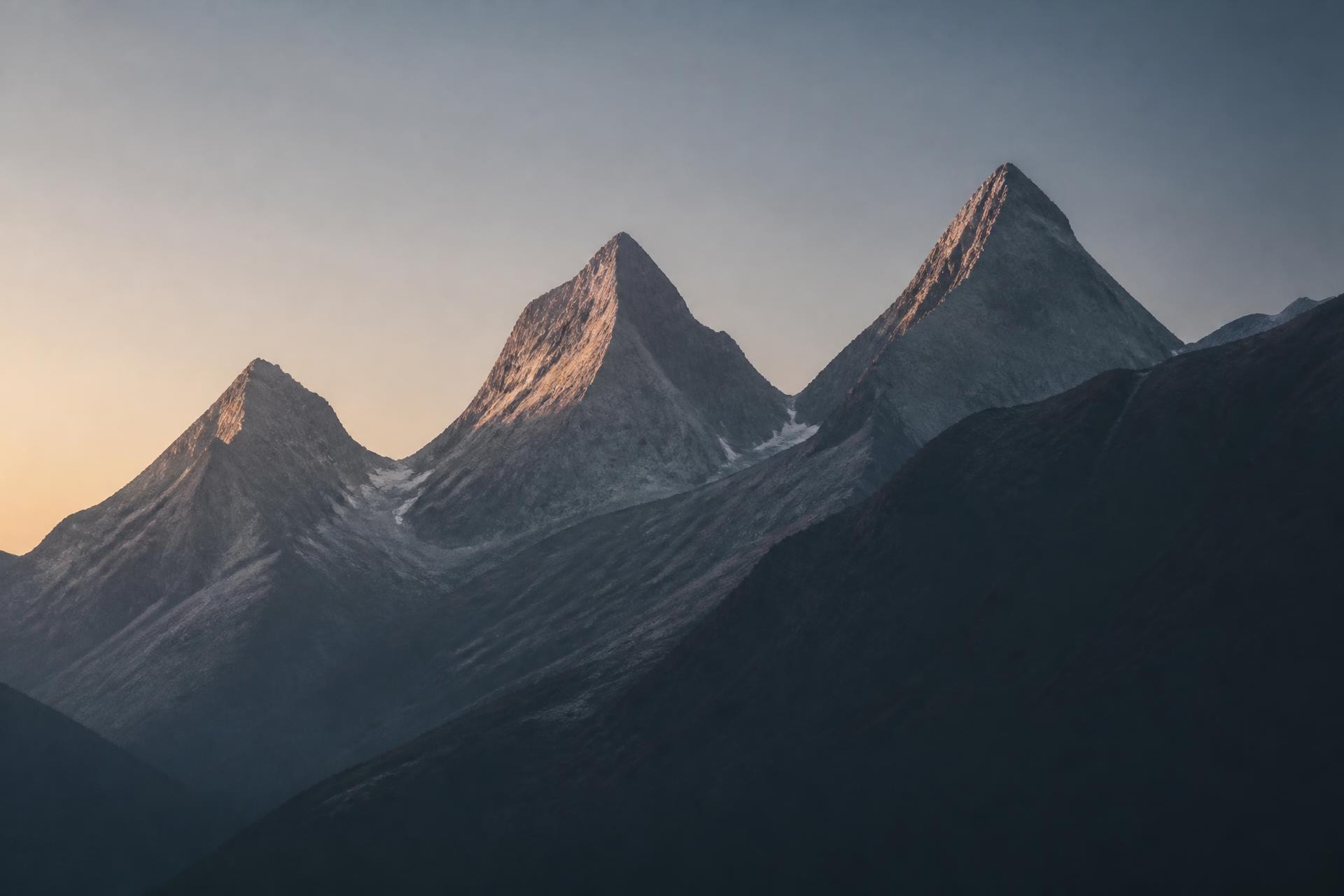 Three mountain peaks in soft early morning light